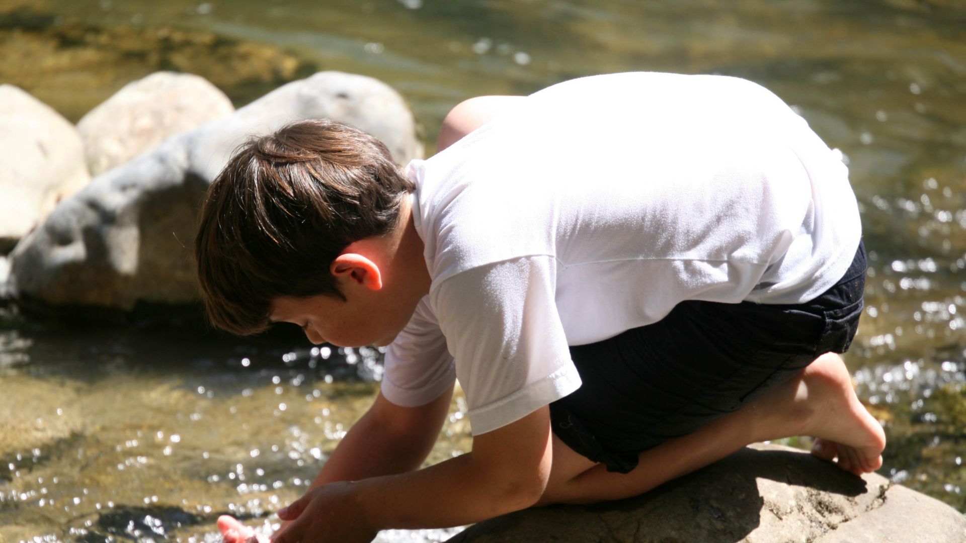 Kind das Wasser aus einem Bach schöpft