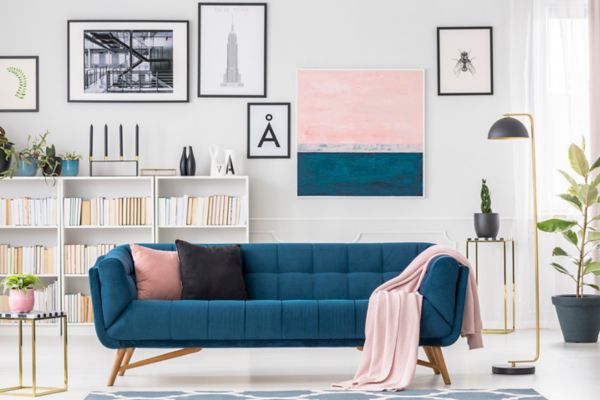 Navy blue settee, cushions, pink blanket and art collection in living room interior