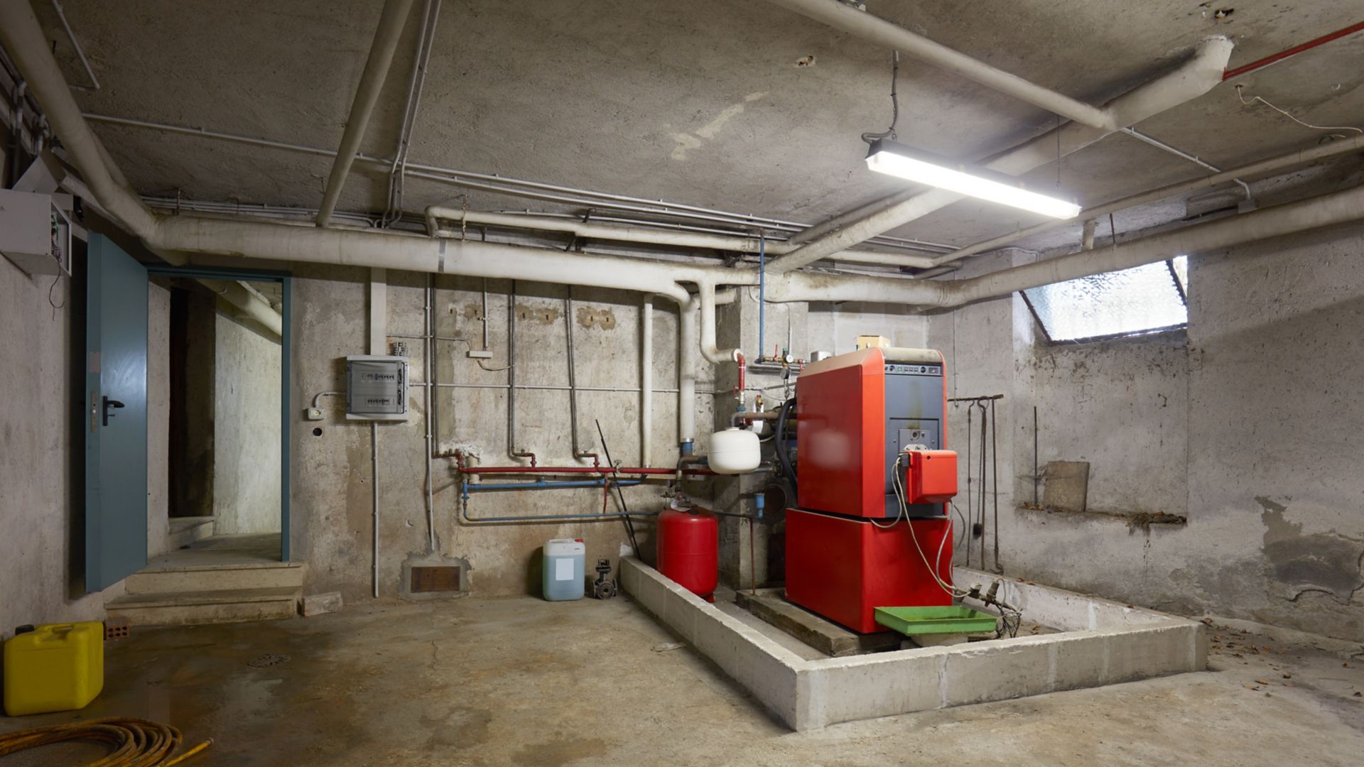 Basement with red heating boiler in old house interior, cement floor