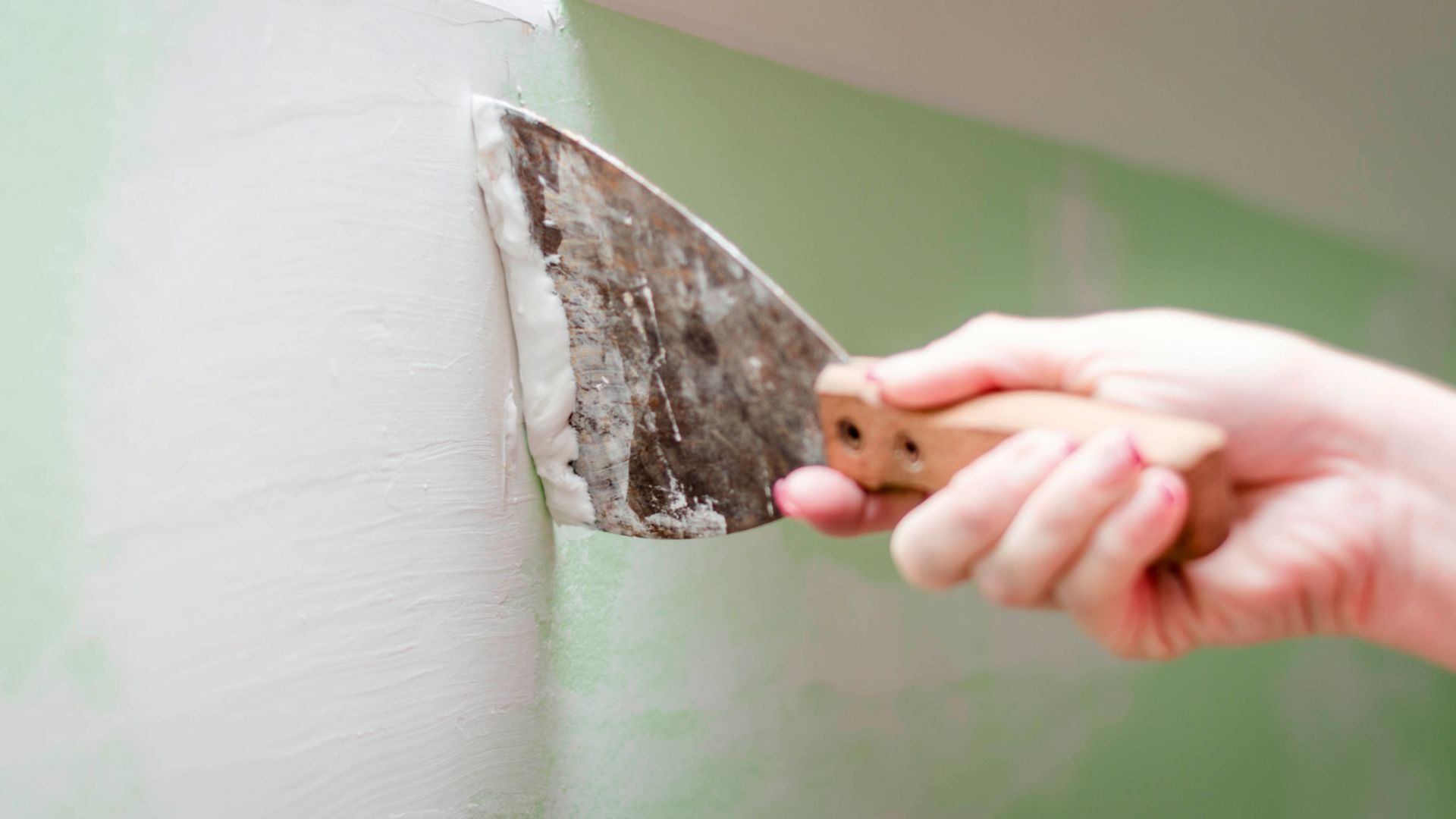 Woman plastering wall at house.