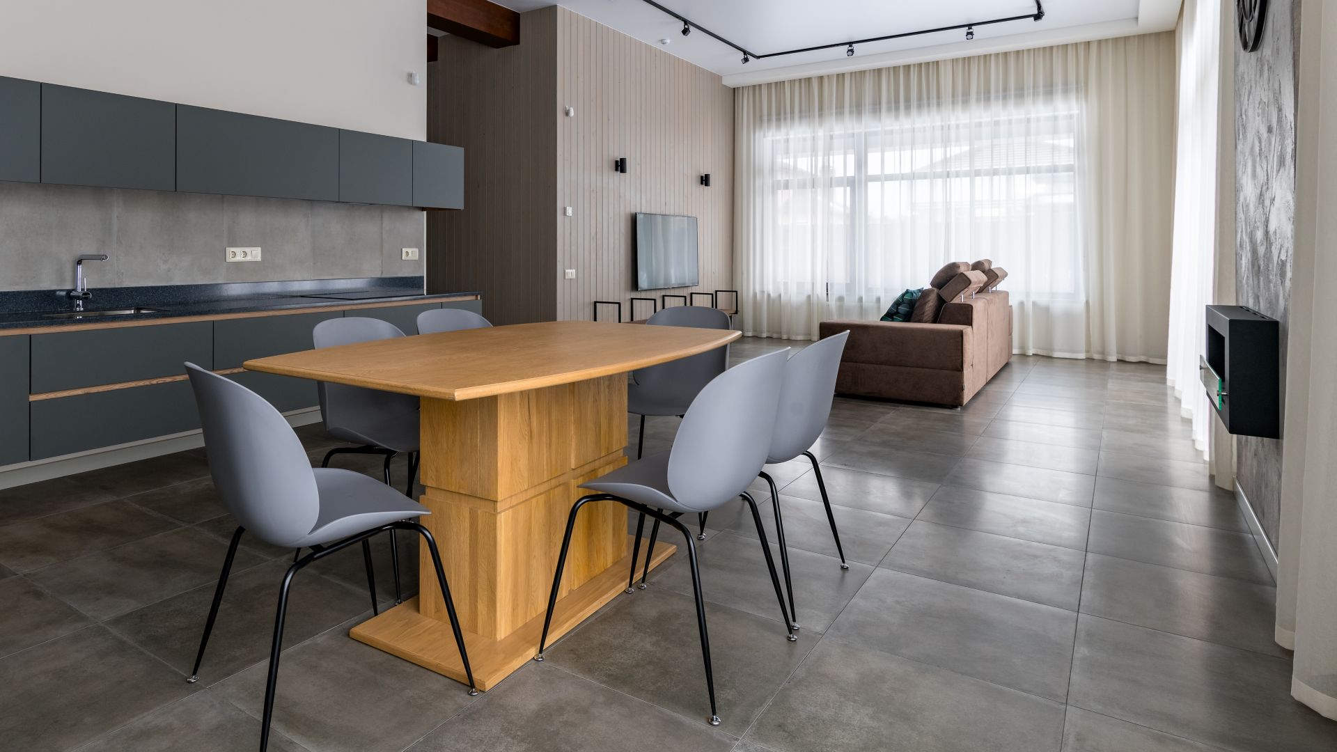 Grey kitchen furniture. Built-in household techie. Black with a gold chandelier over the table. panoramic windows. Light interior. Ceiling sweats. Modern furniture for the dining room.