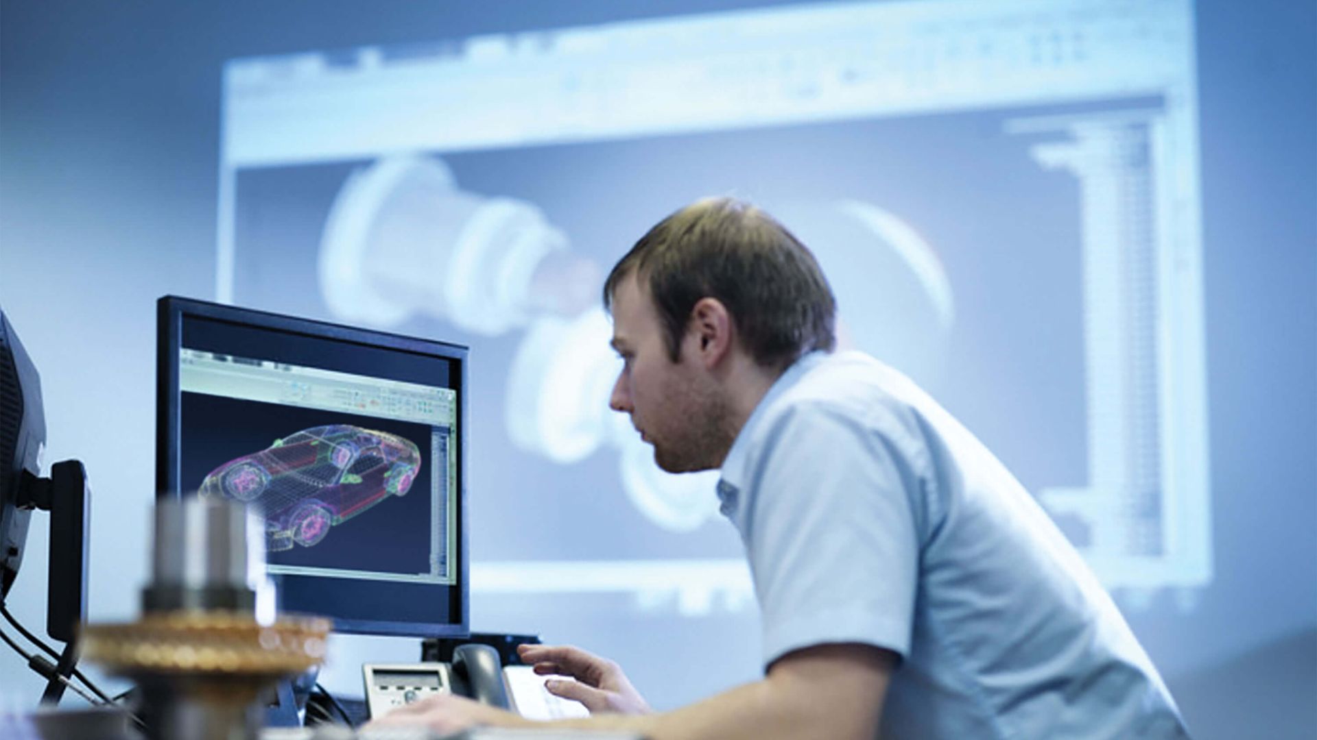 CAD engineer working on desktop computer with picture of vehicle