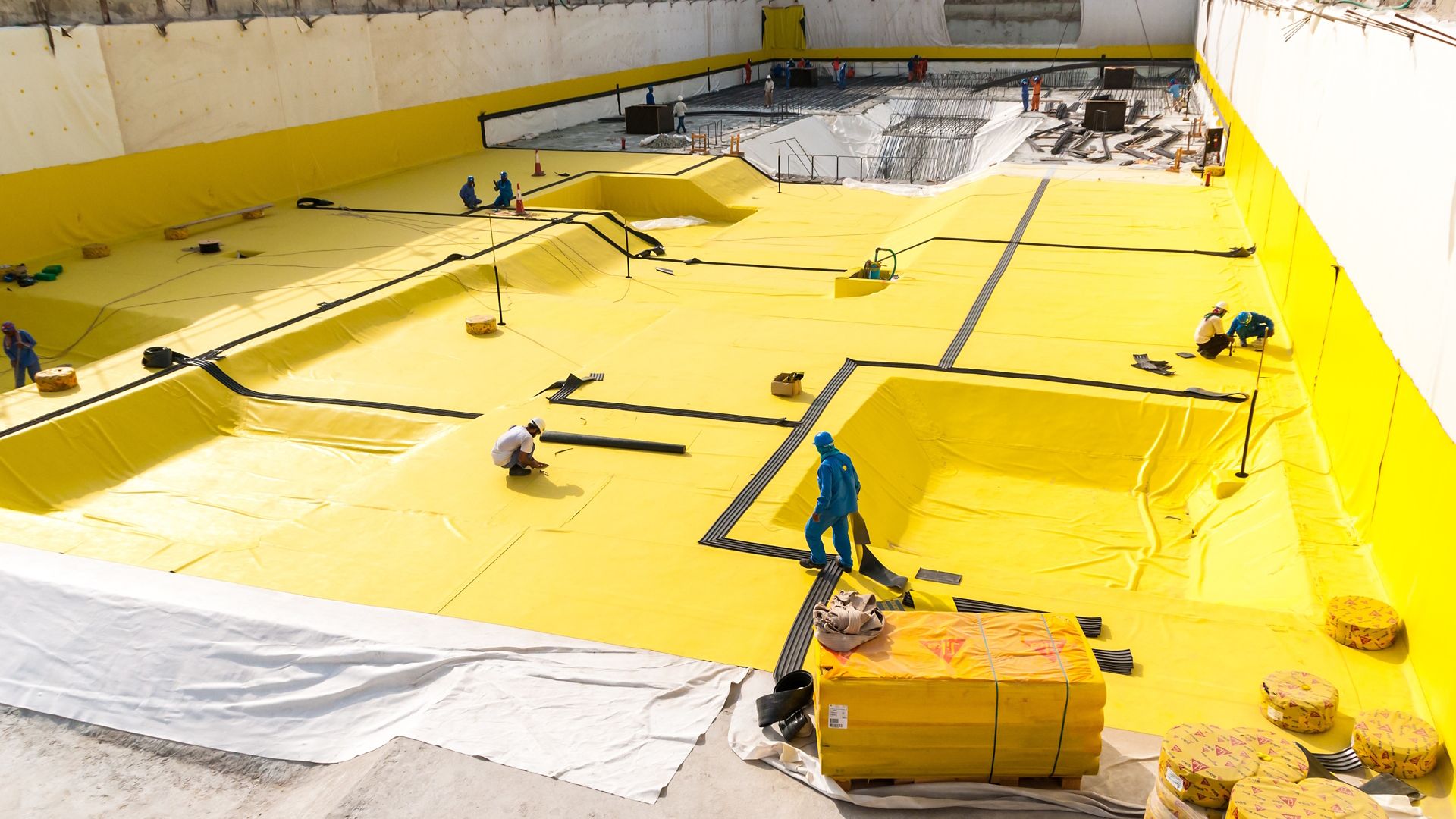    Construction workers applying a below-grade waterproofing membrane	 
