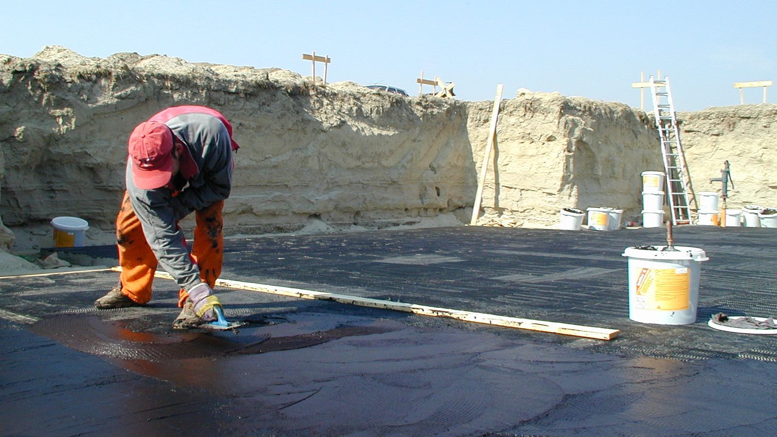 Man applying bituminous membrane on a building basement