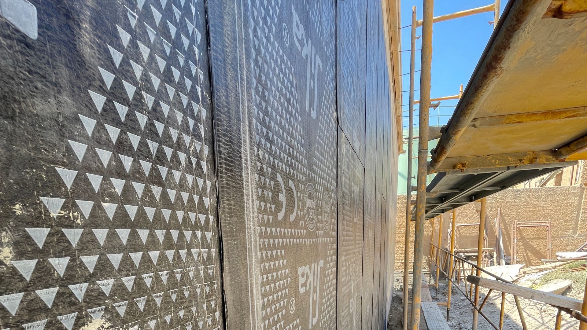 Close up of SikaShield® bitumen waterproofing membrane with scaffolding