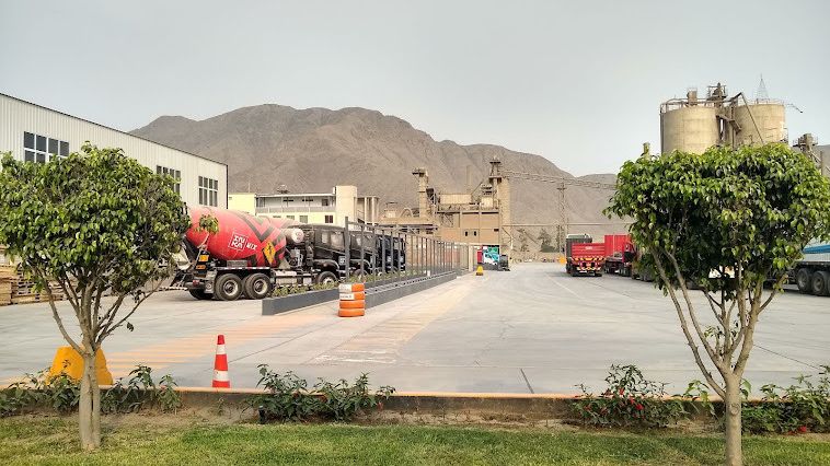 Caliza cemento inca, Lima, Peru, cement trucks infront of a factory in the mountains with green trees.