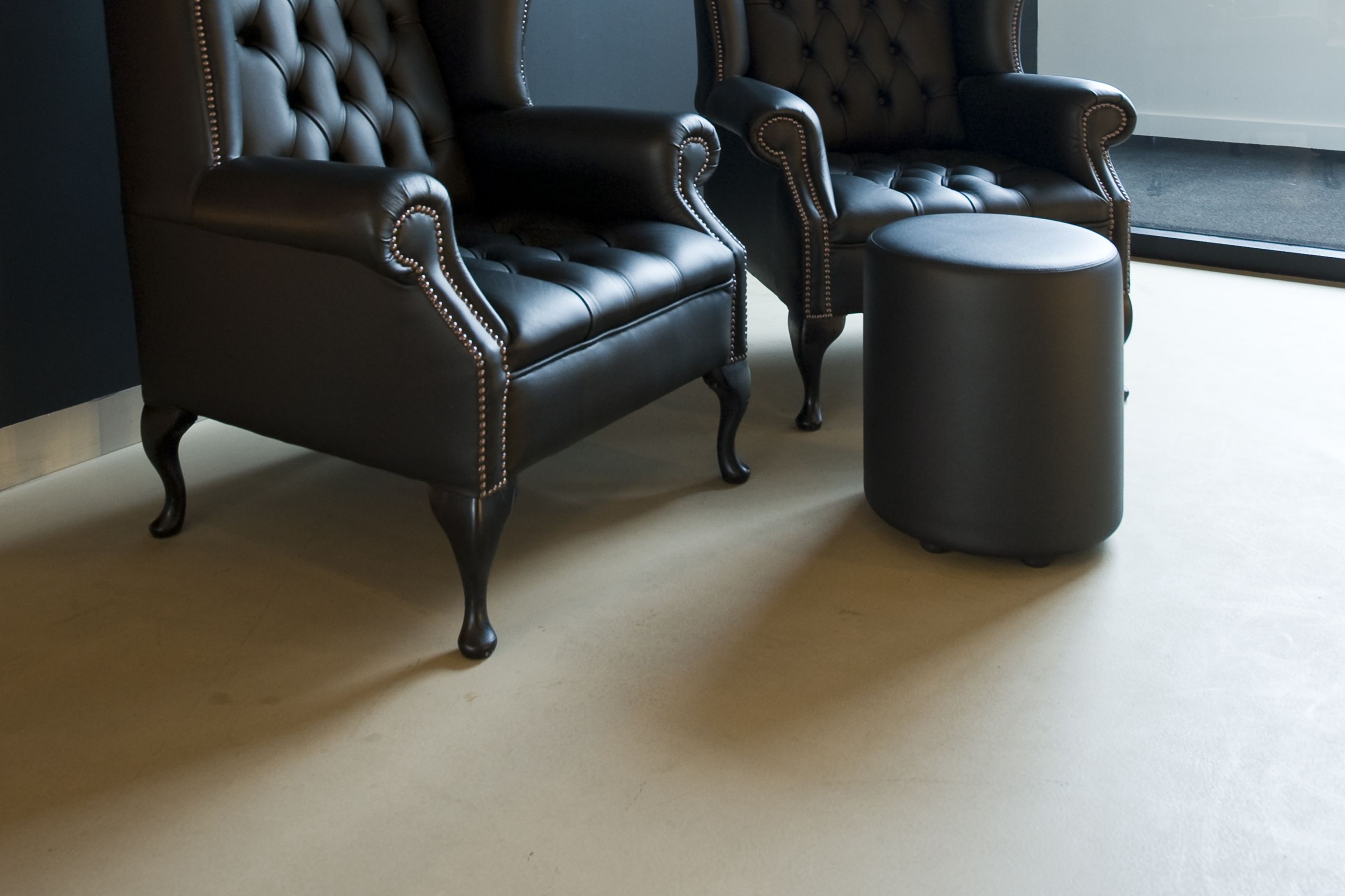 Sika ComfortFloor® beige floor with black wall and armchairs