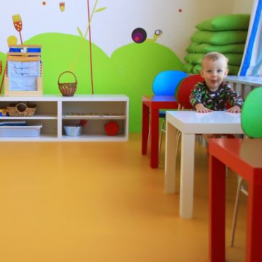 Sika ComfortFloor® orange floor in daycare with baby sitting on chair