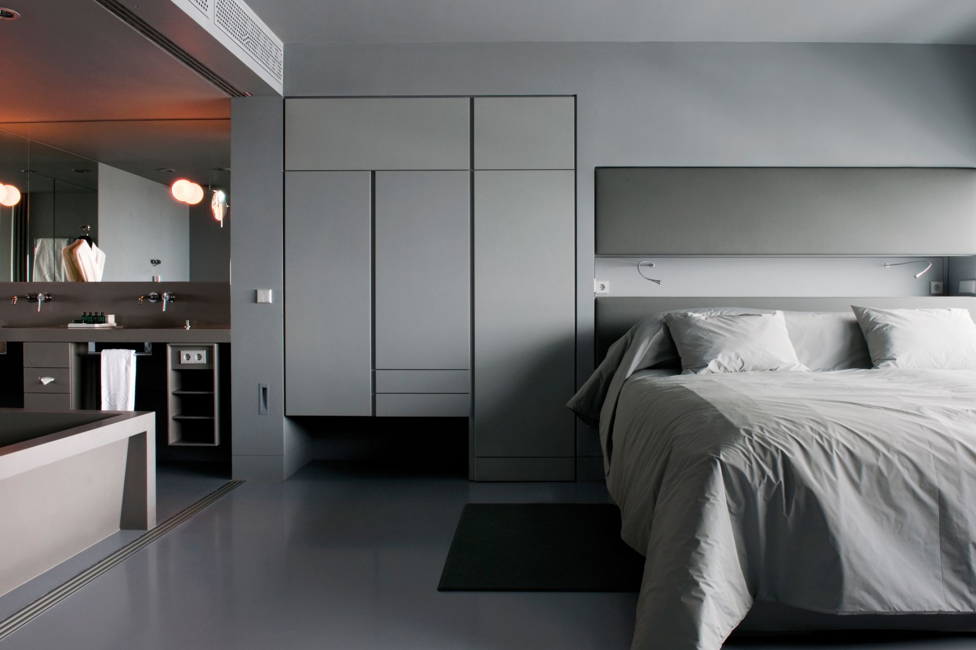 Sika ComfortFloor® grey floor in modern hotel room with bed and bathroom