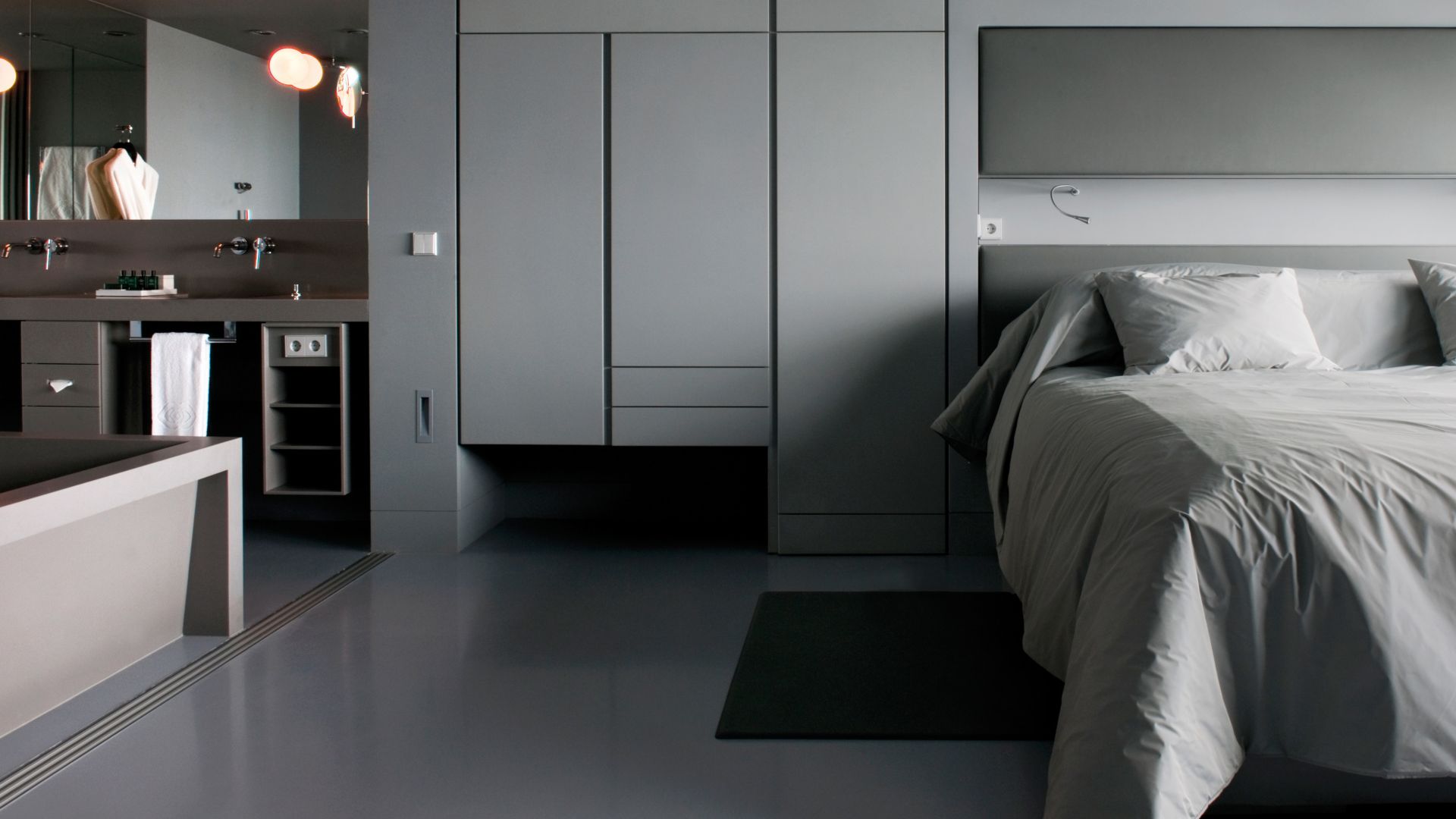 Sika ComfortFloor® grey floor in modern hotel room with bed and bathroom