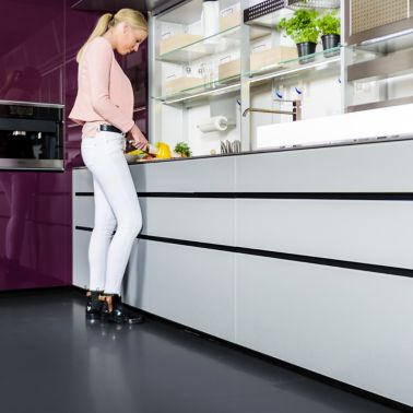 Sika ComfortFloor® dark grey floor in kitchen with woman cutting vegetables