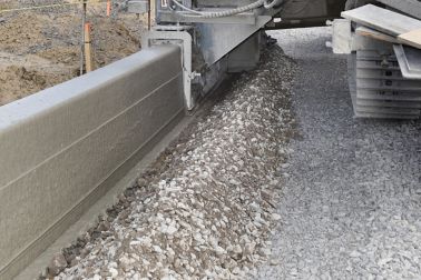 Machine extruding concrete on construction site with concrete fibers