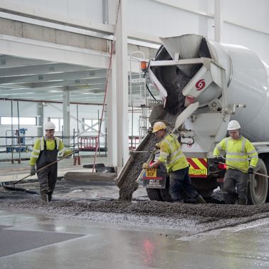 Workers pouring concrete from truck for concrete slab flooring with fibers