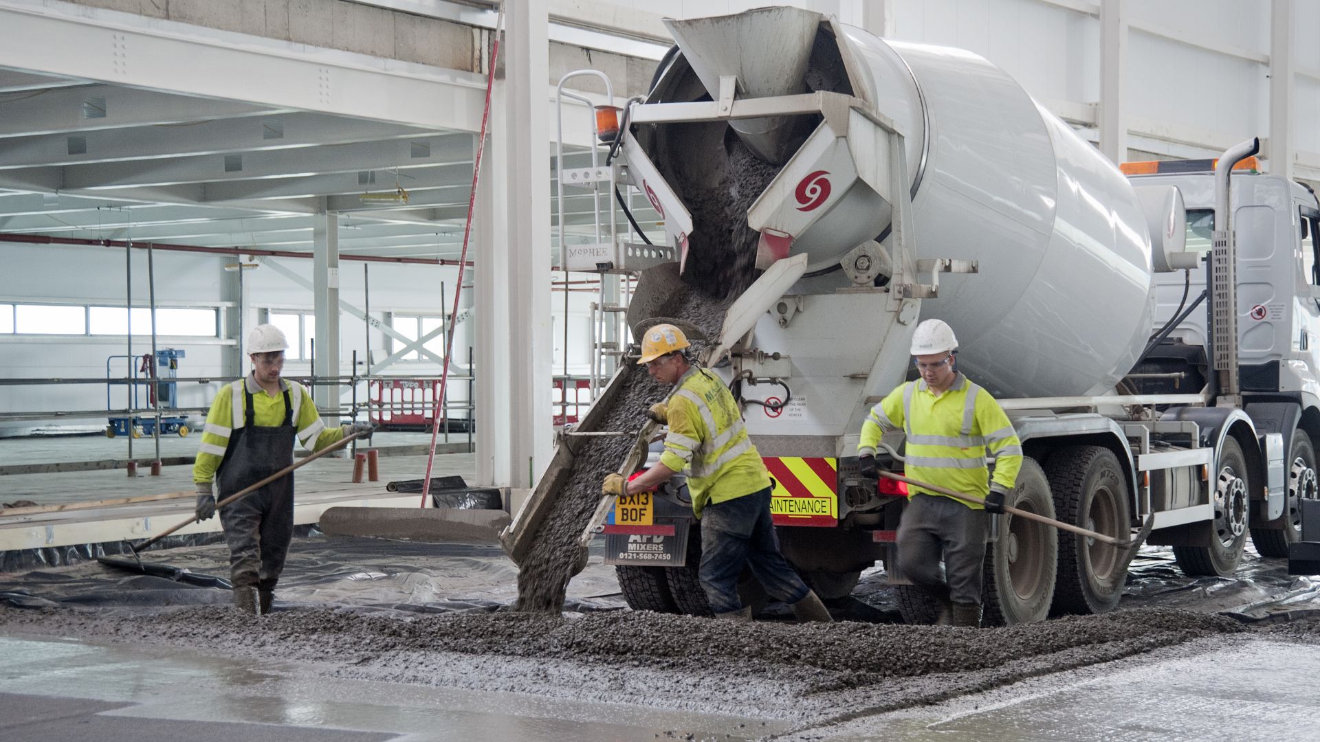 Workers pouring concrete from truck for concrete slab flooring with fibers