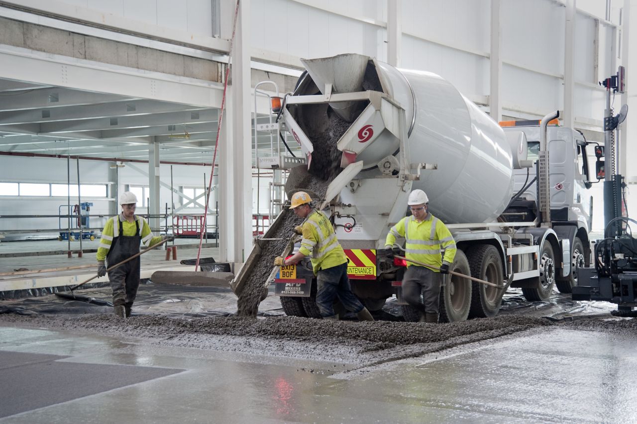 Workers pouring concrete from truck for concrete slab flooring with fibers