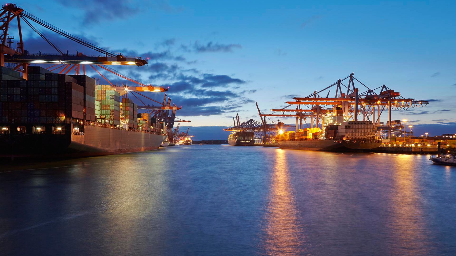 Container vessels are loaded / unloaded at container terminals in the deepwater port Hamburg-Waltershof in the evening. All names on containers, cranes and ships are retouched.