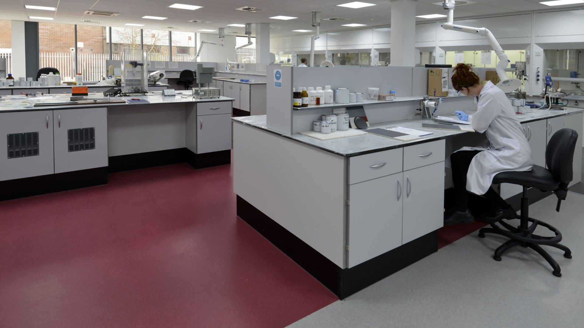 Clean red and white decorative laboratory interior floor with female research technician at work