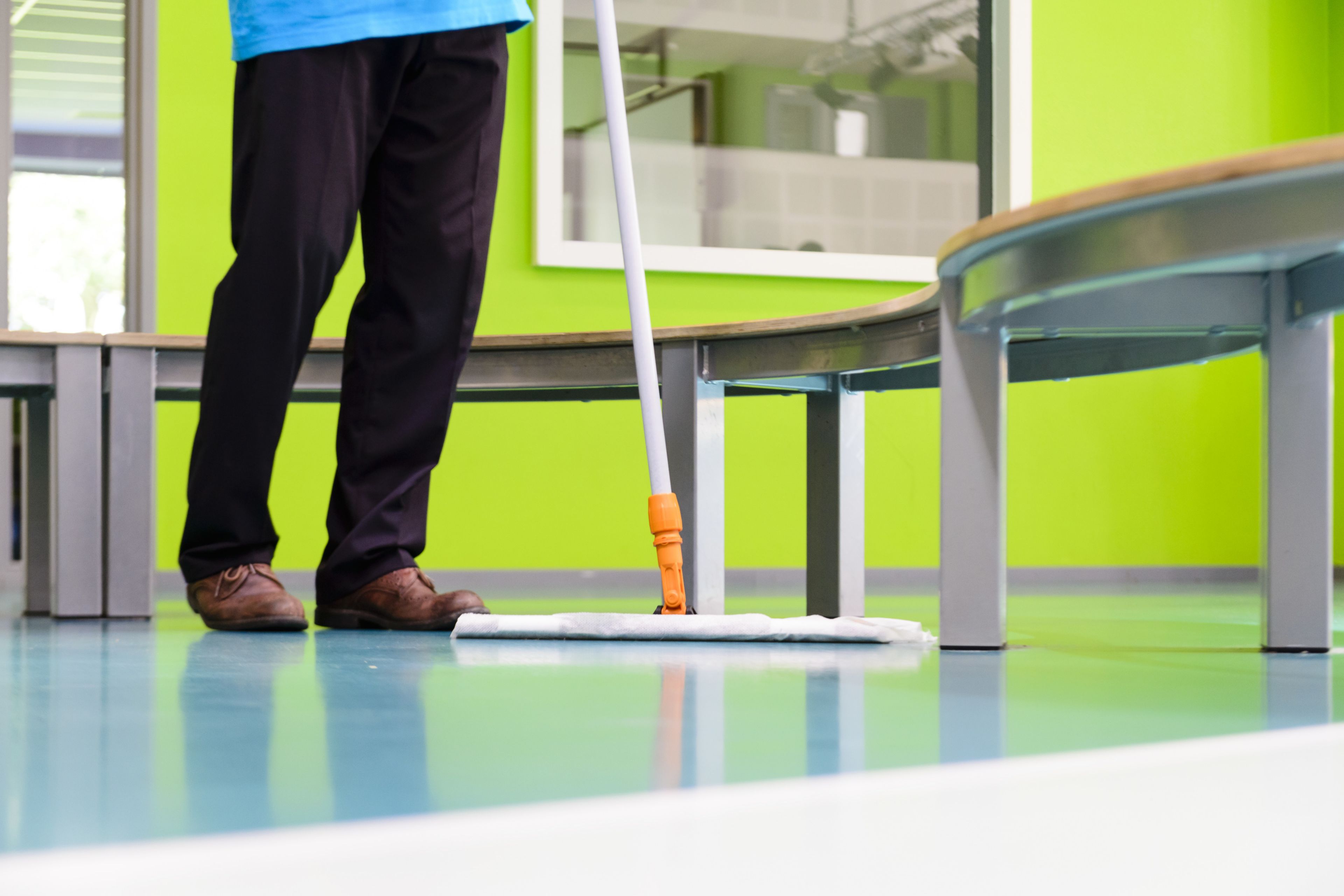 Man sweeping colorful decorative floor Sika ComfortFloor system in Revius Lyceum School in Netherlands