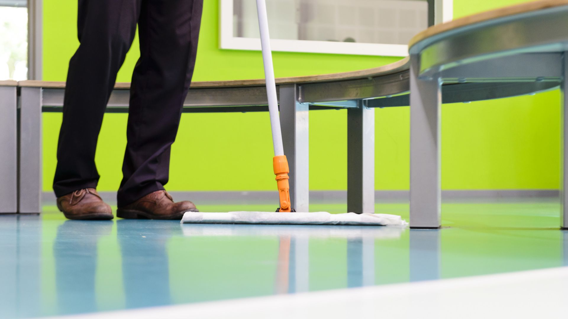 Man sweeping colorful decorative floor Sika ComfortFloor system in Revius Lyceum School in Netherlands