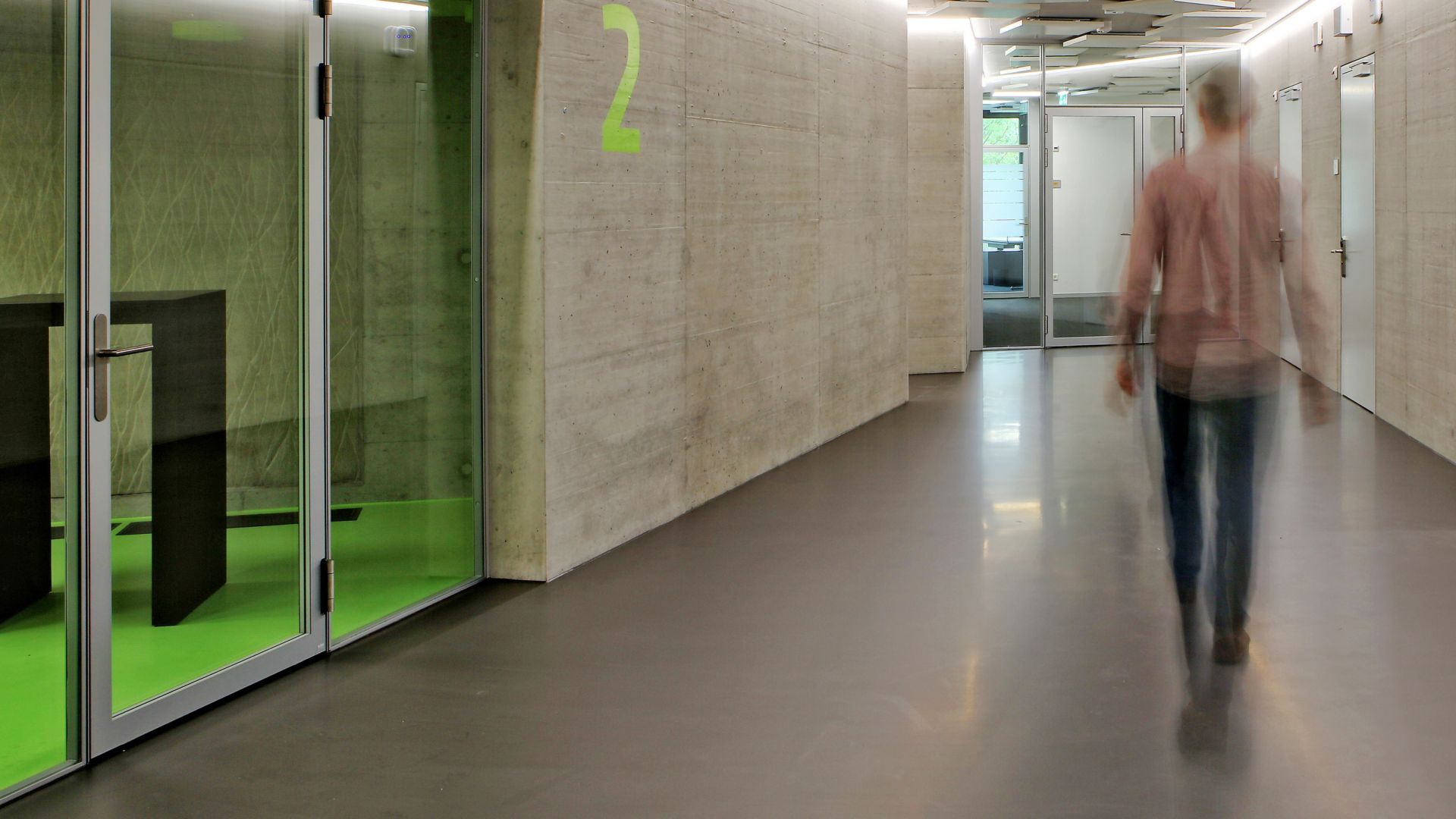 Man walking in corridor office building on grey Sika ComfortFloor concrete walls at Limmat building in Zurich