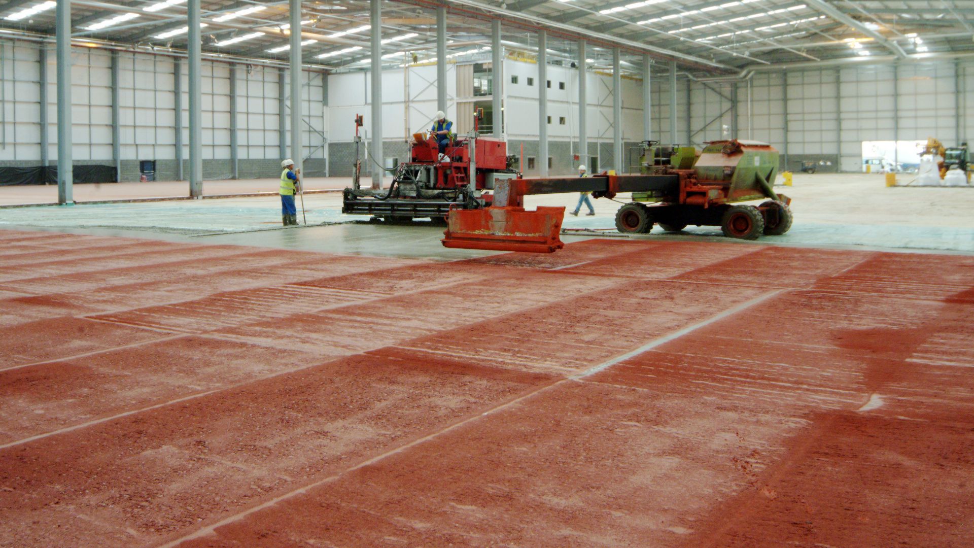 Dry shake hardeners broadcasted directly onto fresh concrete floor in warehouse