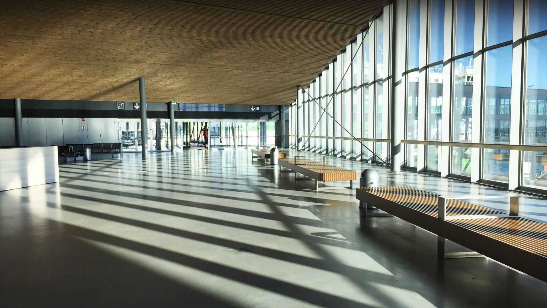 Polished grey concrete floor in airport with shadows and glass windows