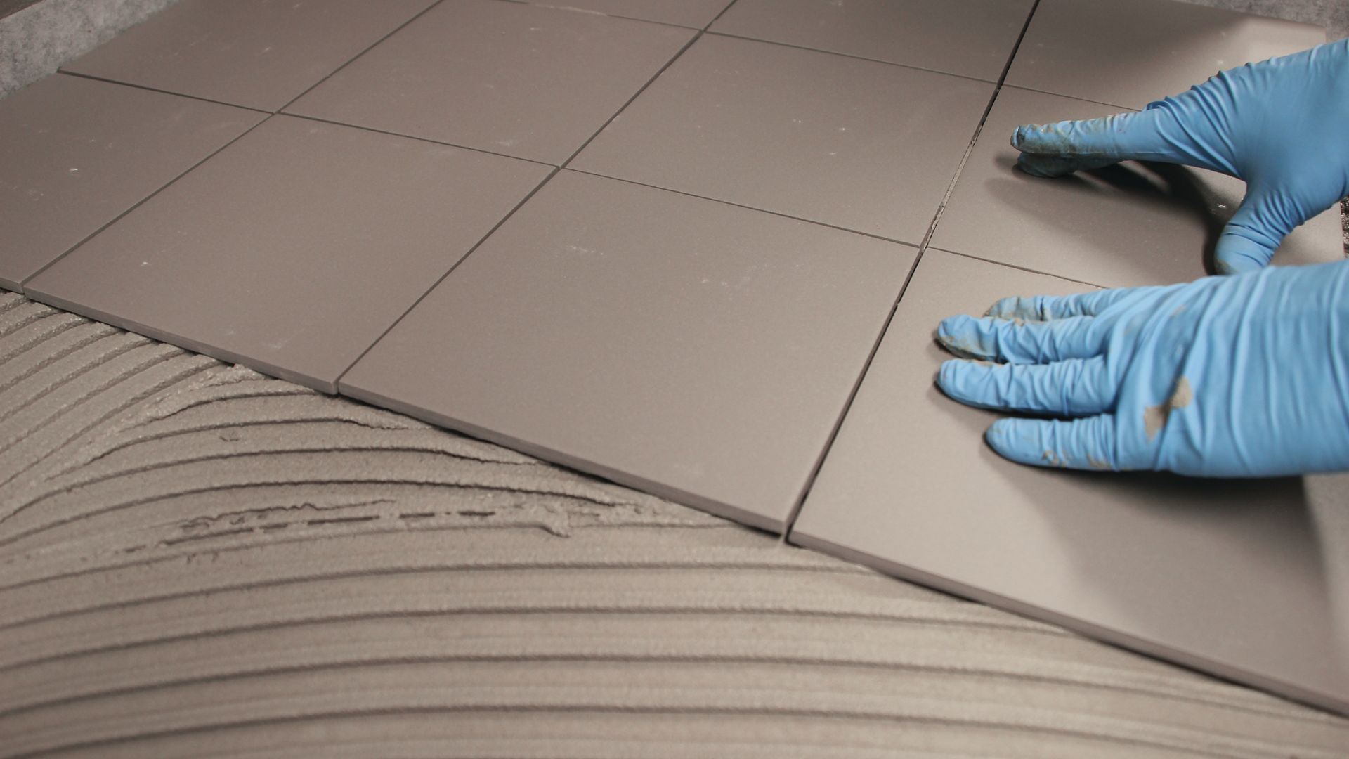 Application of ceramic floor tiles onto adhesive