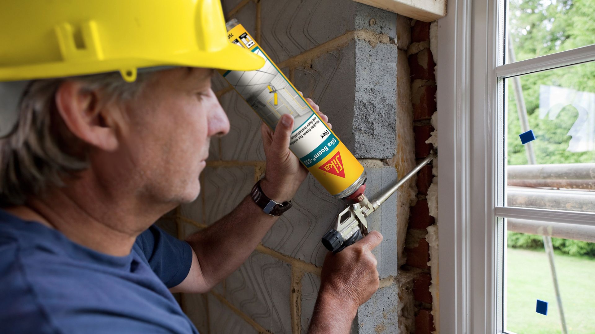 Man applying Sika Boom expansion foam between a window and a wall