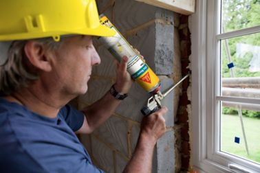 Man applying Sika Boom expansion foam between a window and a wall