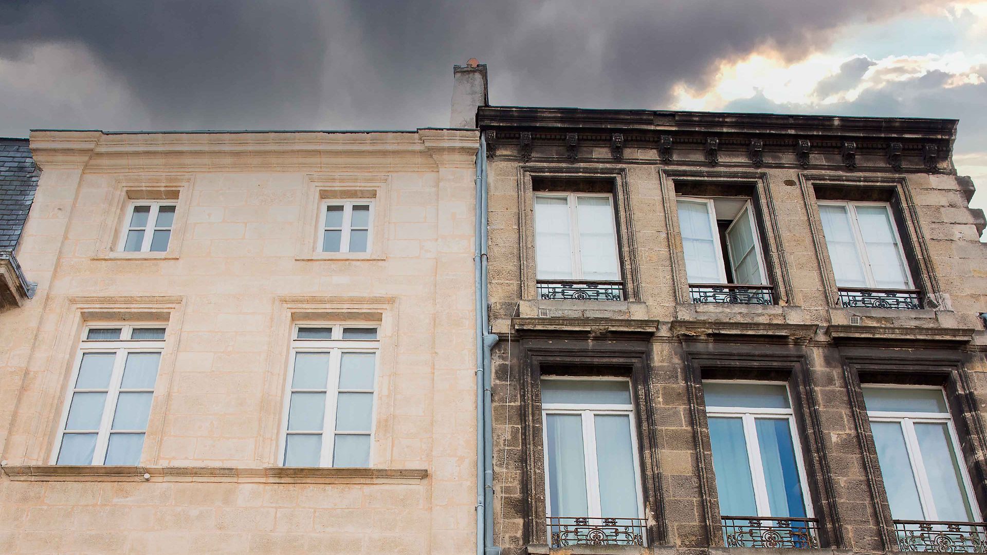 Stone house facade clean white stone vs dirty brown stone before Sika cleaning products with stormy sky