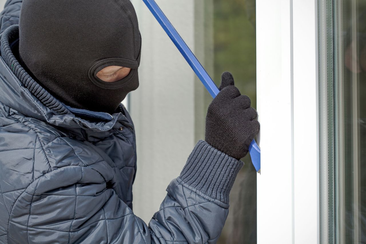 Man trying to break in a house through a burglary proof bonded window