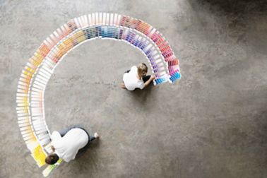 Color swatches paint chips spread out on floor in array with woman and man choosing colors