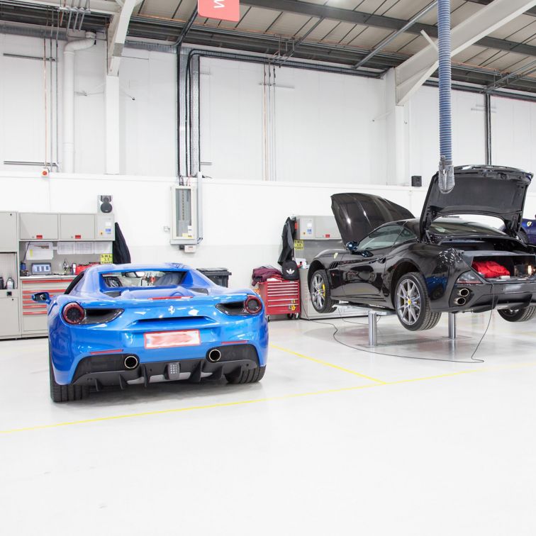 Ferrari cars in repair workshop parked on smooth and seamless floor