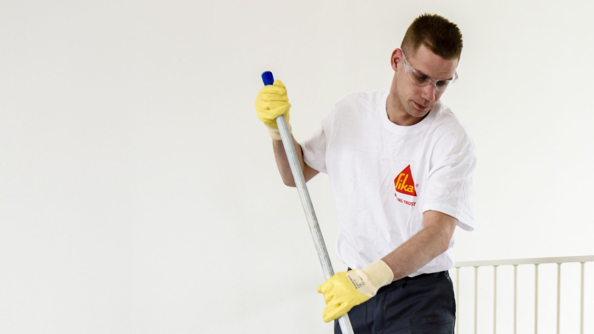 Sika applicator applying blue primer coat to floor tiles