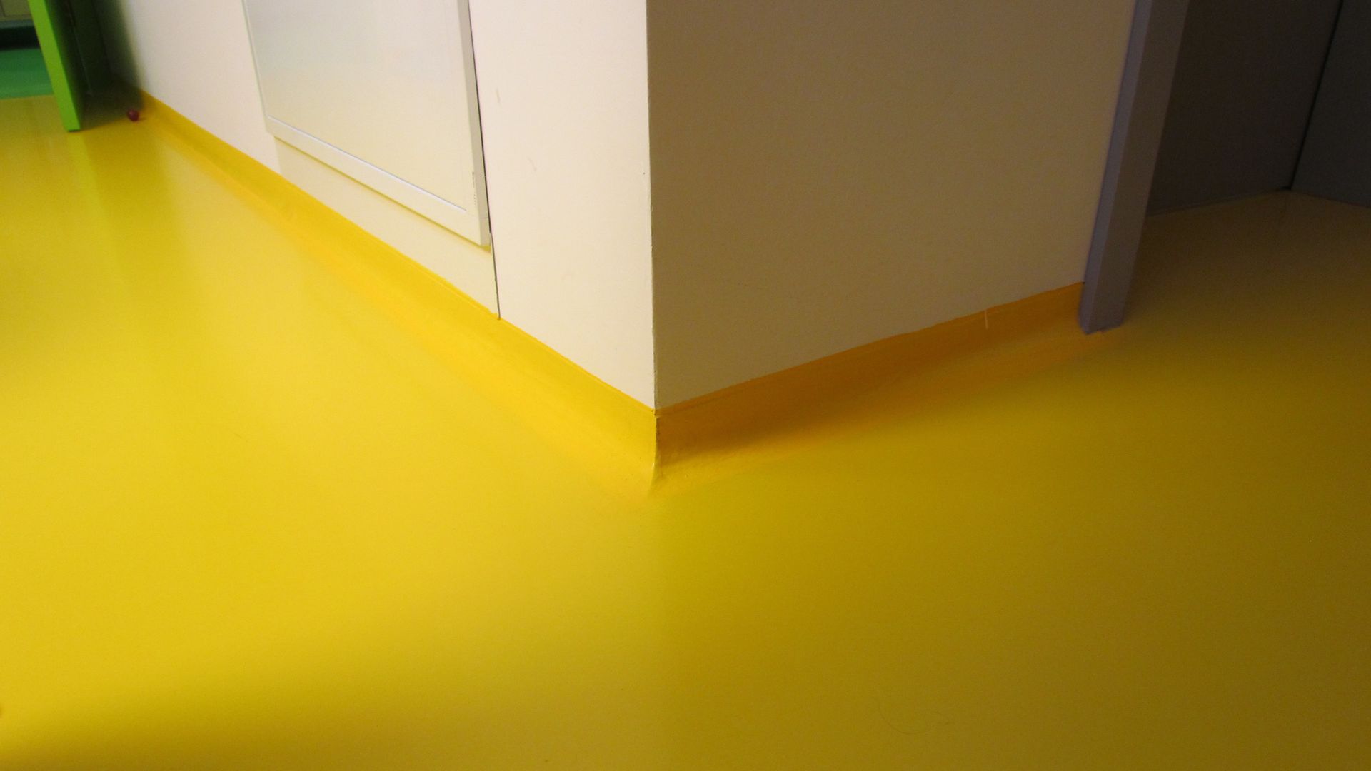 Seamless coving transition detail at floor to wall connection in yellow floor
