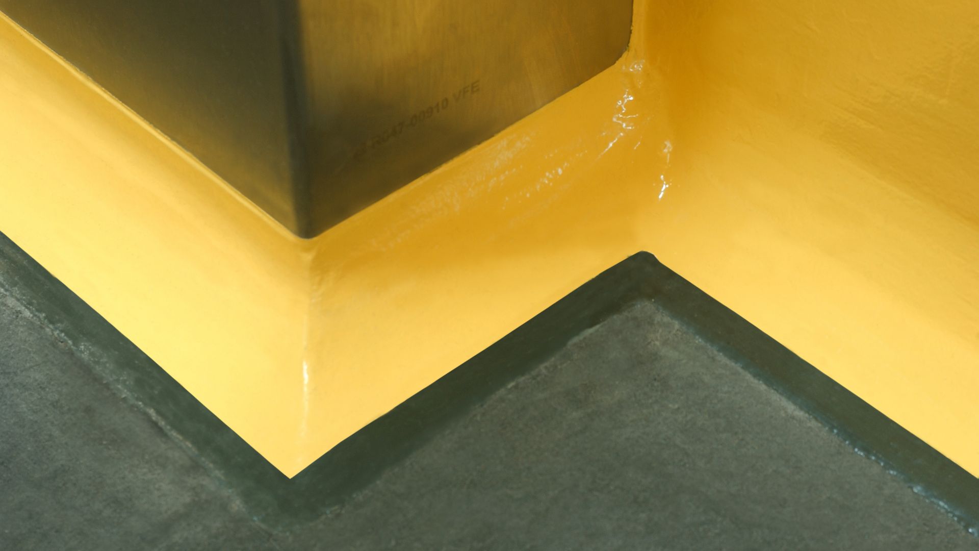 Yellow floor to wall coving detail at seamless joint between wall and floor with Sikagard