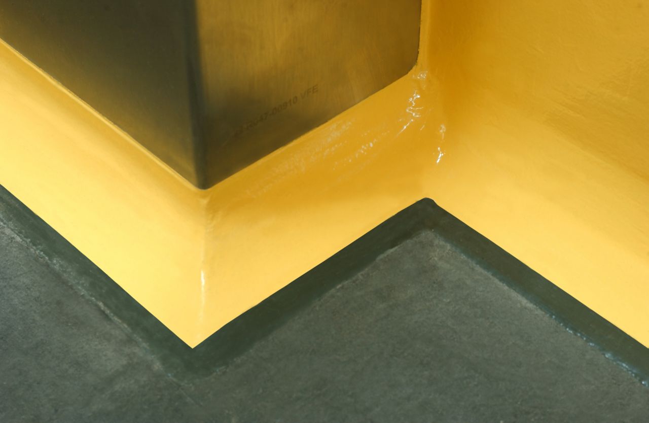 Yellow floor to wall coving detail at seamless joint between wall and floor with Sikagard