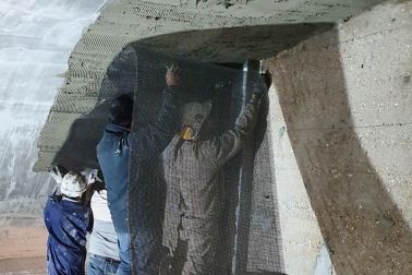 Men installing FRCM with mortar on ceiling