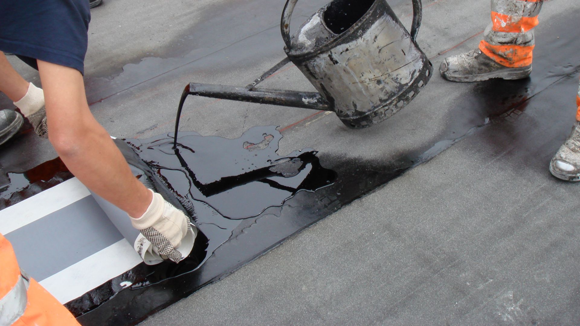 Two workers applying hot melted bitumen membrane	