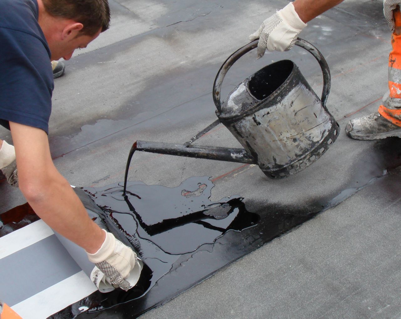 Two workers applying hot melted bitumen membrane	