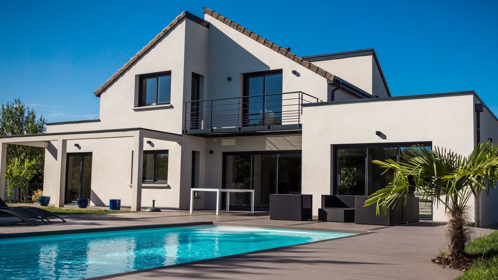 House with white thermal insulated facade pool pitched roof blue sky