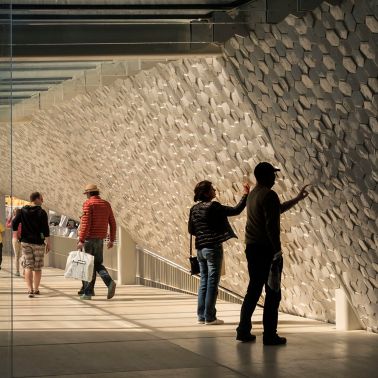 People touching hexagon shaped tiles on facade of Leixoes Cruise Terminal 