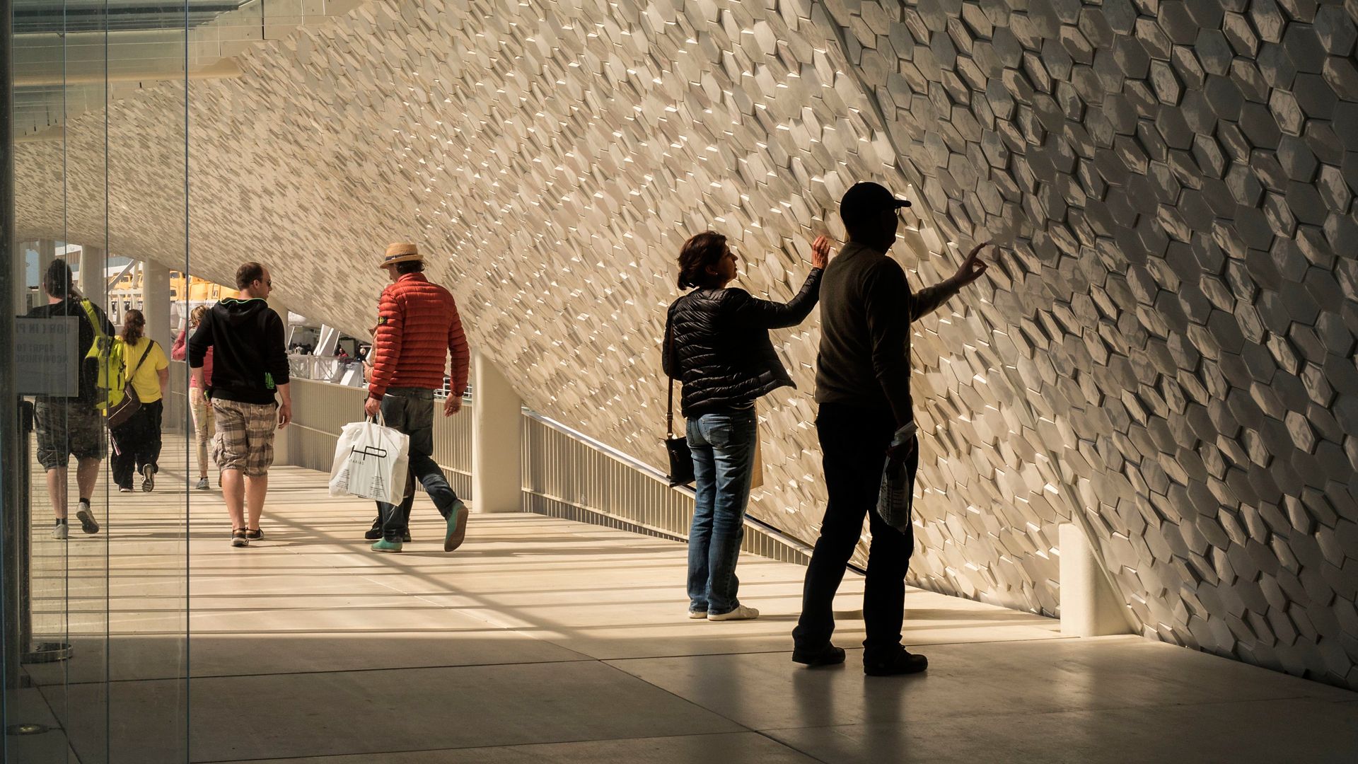 People touching hexagon shaped tiles on facade of Leixoes Cruise Terminal 