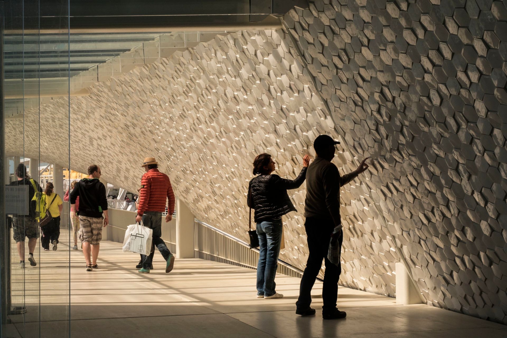 People touching hexagon shaped tiles on facade of Leixoes Cruise Terminal 