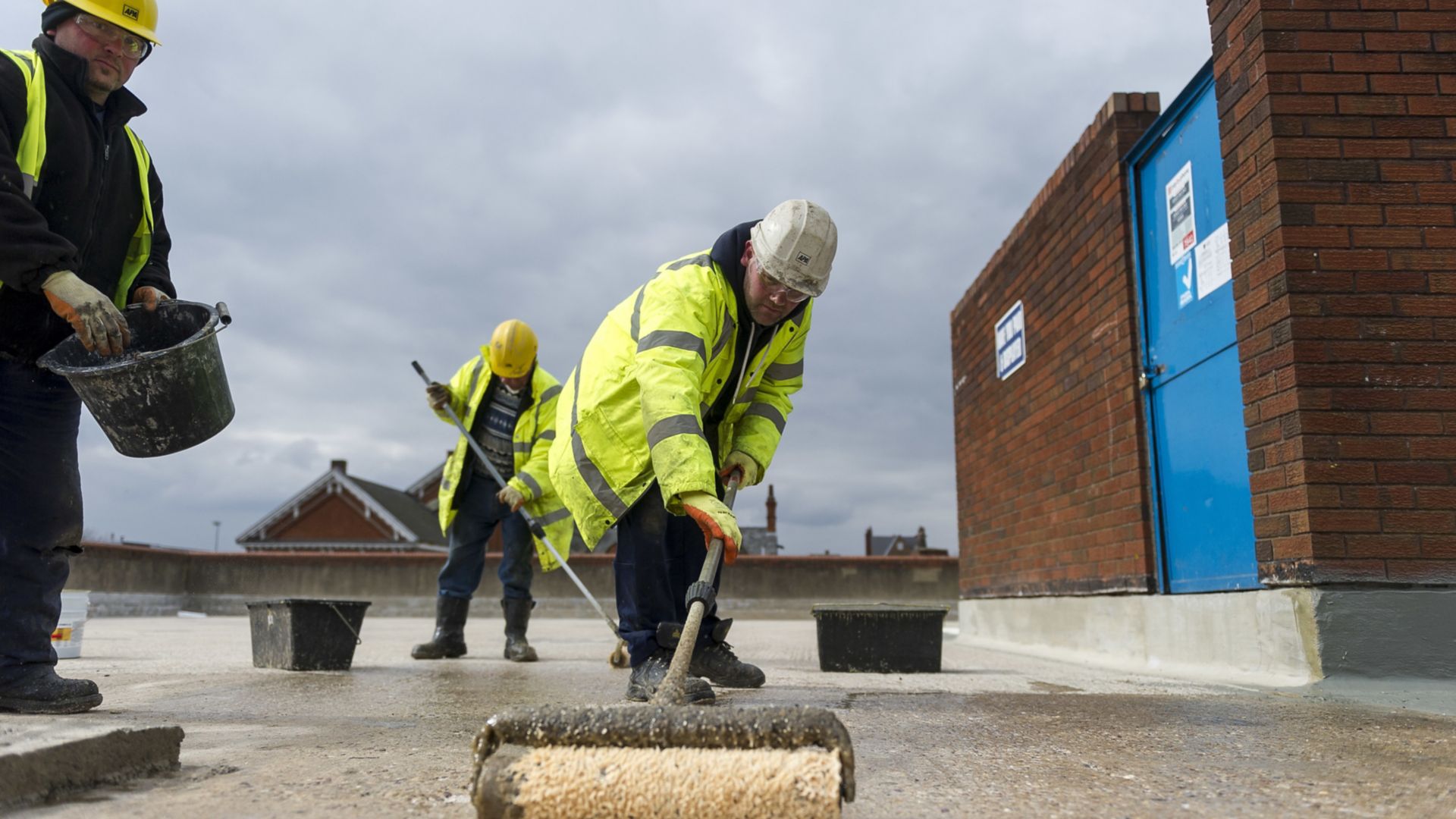 Construction workers applying Sikalastic liquid applied membrane on parking garage surface