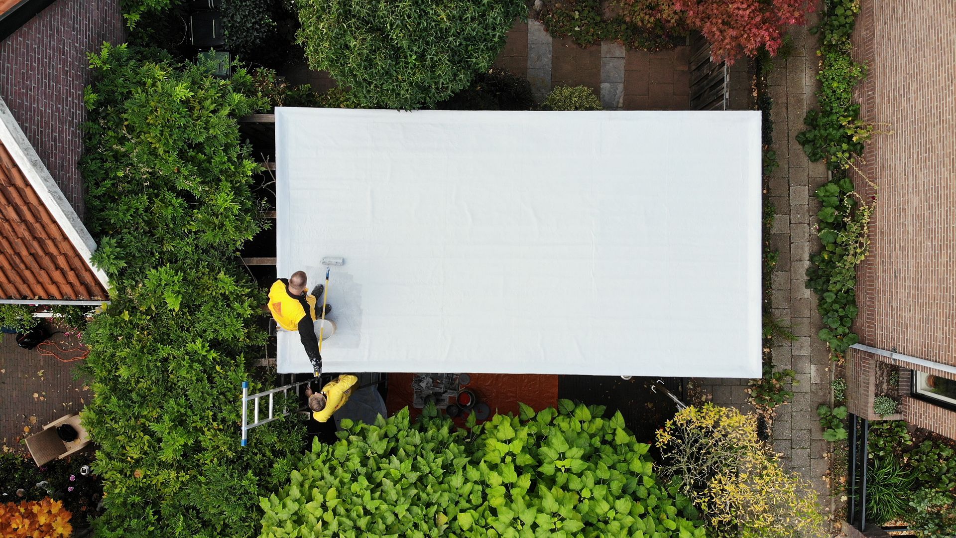 Construction workers applying Sikalastic-580 liquid applied membrane on the roof drone view