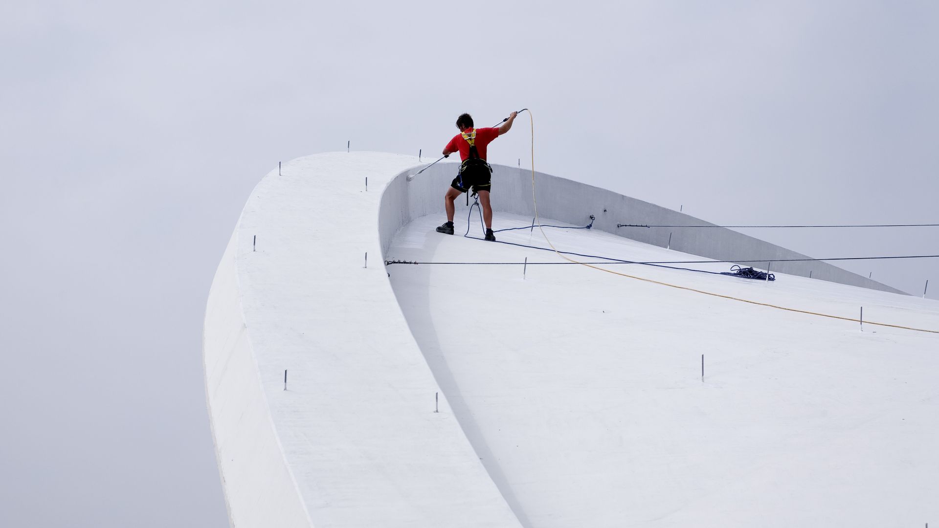 Construction worker applying Sikalastic liquid applied membrane on Congress Hall roof in Berlin Germany