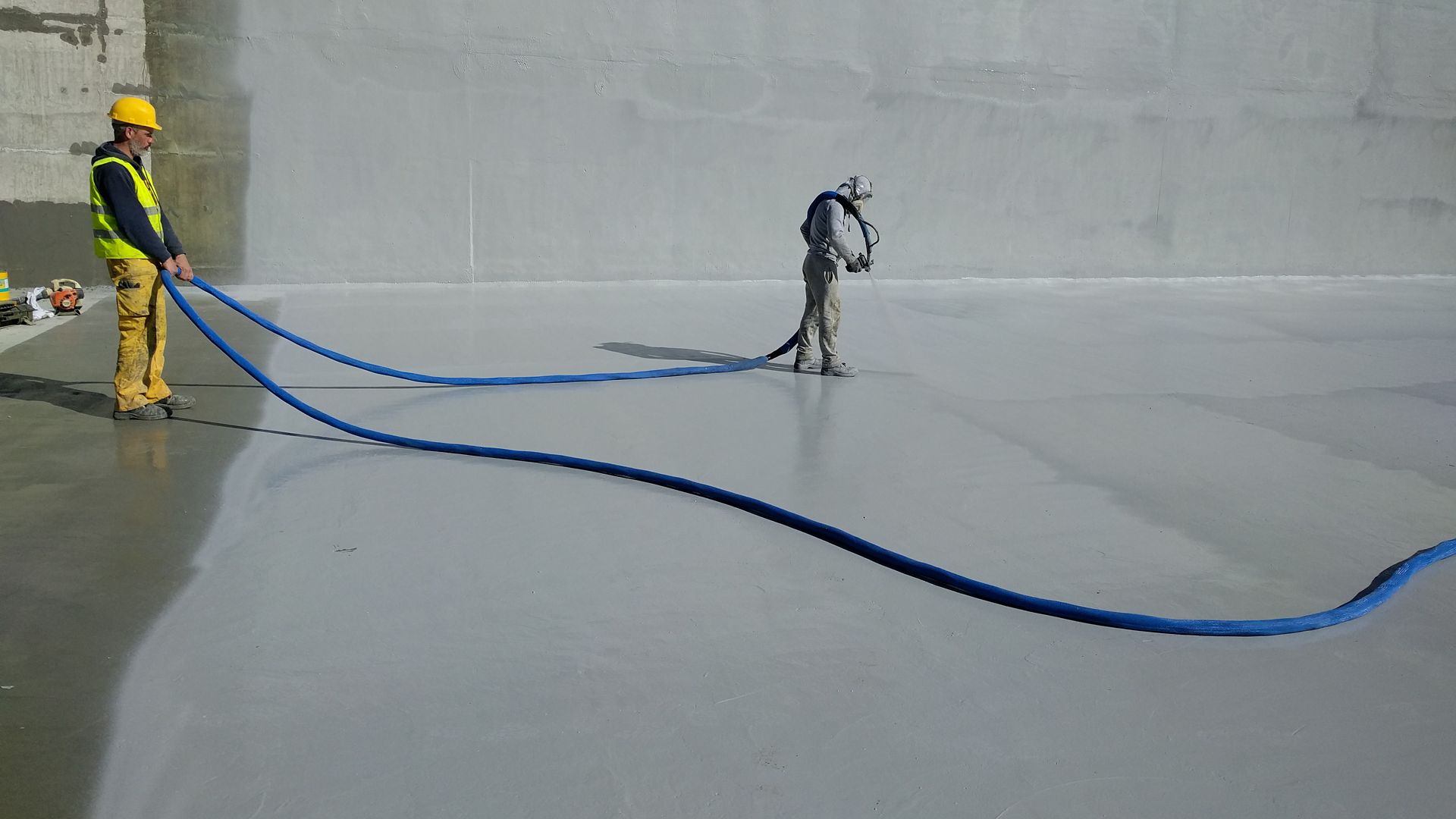 Two men spraying liquid-applied membrane 