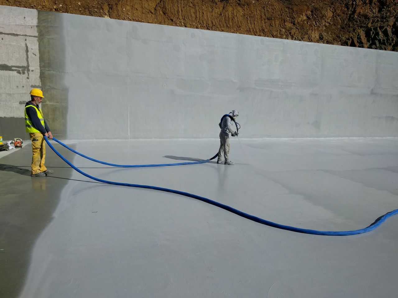 Two men spraying liquid-applied membrane 