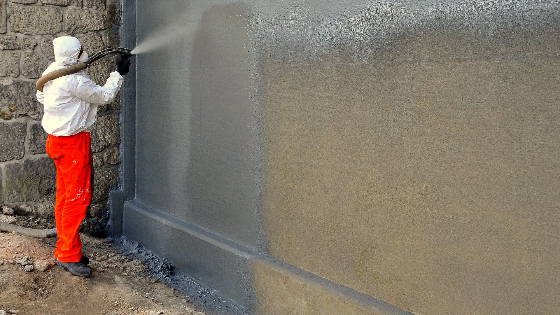 Man spraying liquid-applied membrane on a wall